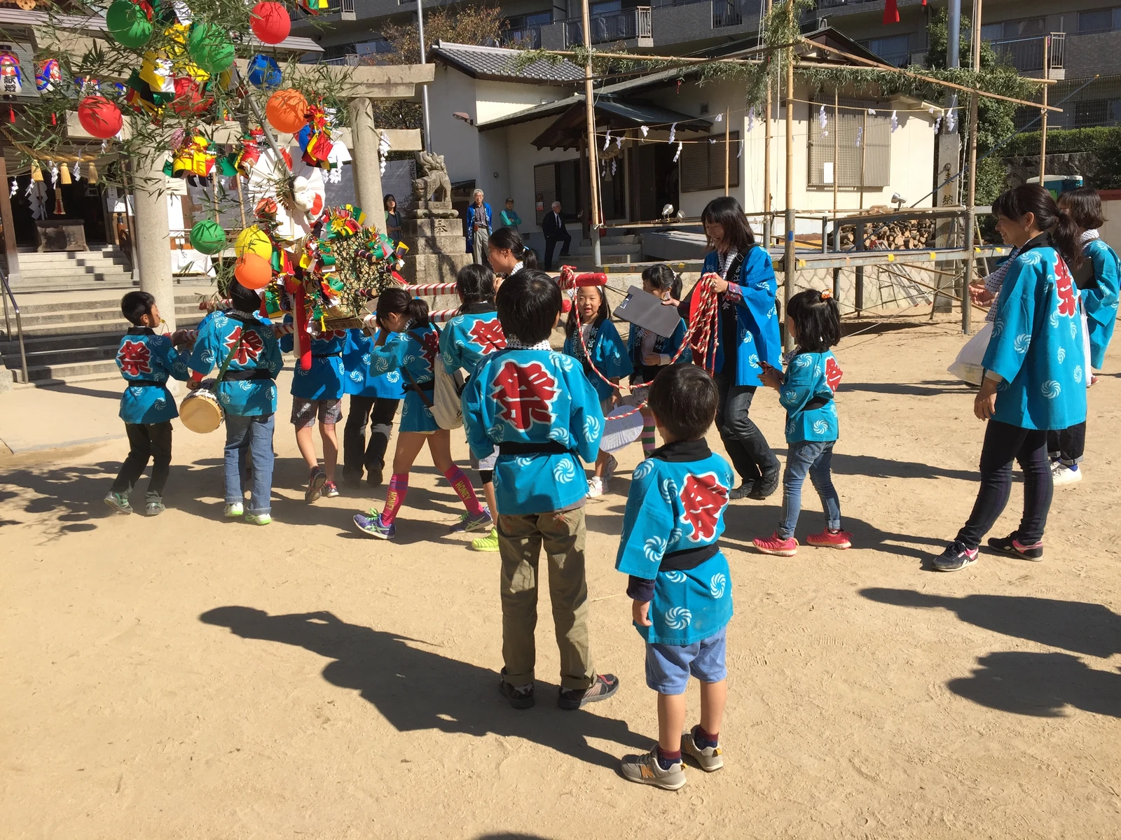 青いはっぴを着て、地域のお祭りに参加する子どもたち