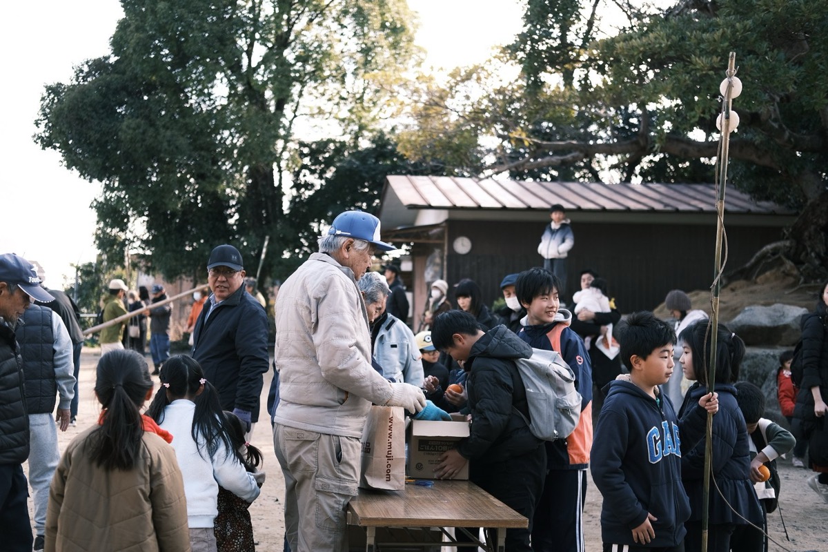 新宮神社のとんどで子どもたちにみかんを手渡す様子